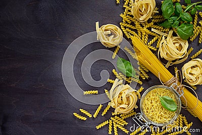 Various types of pasta with basil on a kitchen wooden table. The concept of Italian food. Stock Photo