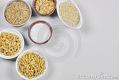 Various uncooked pasta bowls on white background with flour Stock Photo