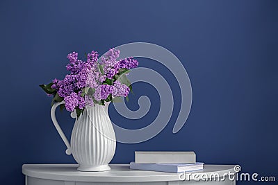 Vase with beautiful blossoming lilac on table against color background Stock Photo