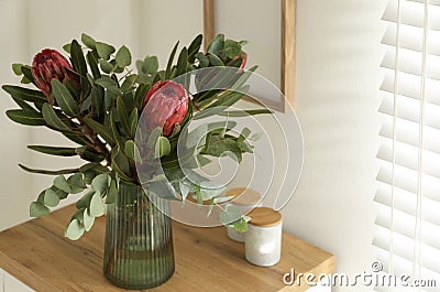 Vase with beautiful Protea flowers on table indoors Stock Photo