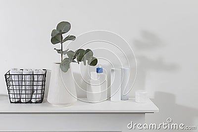 Vase with a eucalyptus branch, plastic bottles of shampoo, cream. Bathroom. Space for text. Metal basket with rolled face towels Stock Photo