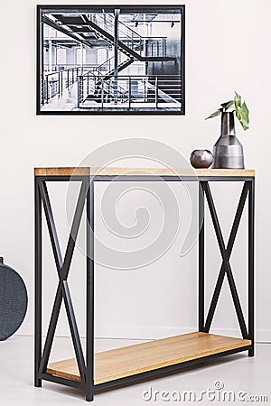 Vase with leaf and candle standing on stylish modern table with metal legs. Industrial poster on the wall Stock Photo