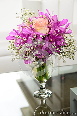 A vase of roses in a bouquet of orchids on a glass table Stock Photo