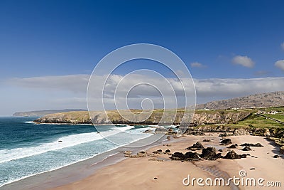 Durness Beach in Scotland, with azure waters, golden sands, dark rocks, surrounded by cliffs and sky Stock Photo