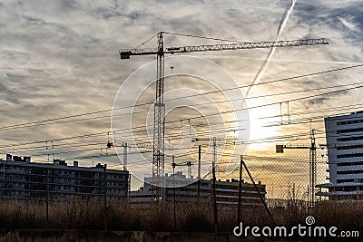 A vast, under construction building stands tall against the horizon of a cloudy sky, with a massive crane towering above it Stock Photo