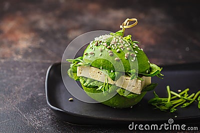 Vegan avocado tofu burger on black dish. Healthy detox food, plant based food concept Stock Photo