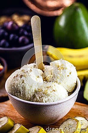 Vegan banana ice cream made with frozen bananas and tropical fruits in the background, without adding chemicals. Healthy dessert Stock Photo