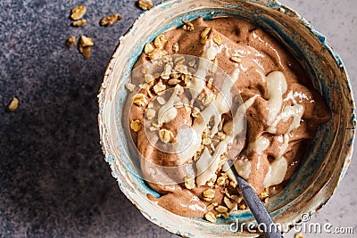 Vegan breakfast. Chocolate banana smoothie bowl with granola and nut butter, top view Stock Photo