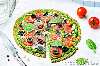 Vegan broccoli zucchini pizza crust with spinach pesto, tomatoes, onion and olives Stock Photo