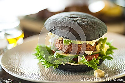 Vegan burger. Black bun, tofu-avocado salad, mayonnaise, cucumber, tomato, fresh salad. Delicious healthy hamburger food Stock Photo