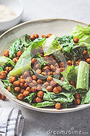 Vegan caesar salad with fried spicy chickpeas in a gray bowl Stock Photo