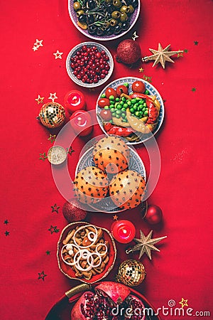 Vegan Christmas appetizers, olive, orange, fruits, vegetable salads, candles, tangerine, pomegranate, star glitter sparkles on red Stock Photo