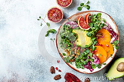 Vegan, detox Buddha bowl with turmeric roasted chickpeas, greens, avocado, persimmon, blood orange, nuts and pomegranate. Stock Photo