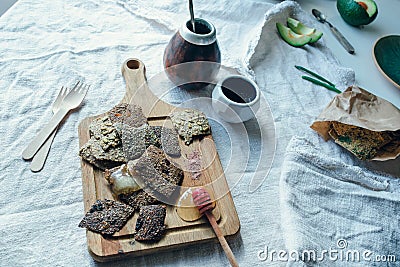 Vegan linnen crackers on a wooden board together with calabash, saucer, plate, cutlery lieing on a rough linnen fabric Stock Photo