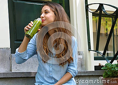 Vegan meal and detox break time concept. Beautiful girl sitting outside her home drinking green juice. Healthy detox vegan diet Stock Photo