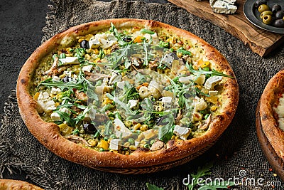 Vegan pizza with green bean pods, broccoli, cauliflower, bell peppers, mushrooms, peas, corn, arugula, olives and cheese on wooden Stock Photo