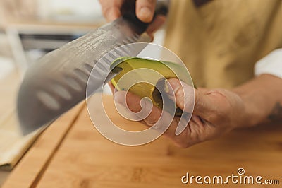 vegan sushi. Close up wide angle asian sushi master slicing avocado with knife Stock Photo