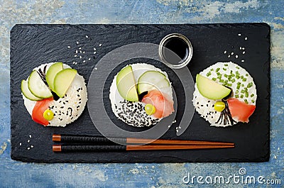 Vegan sushi donuts set with pickled ginger, avocado, cucumber, chives, nori and sesame on blue background. Sushi-food hybrid trend Stock Photo