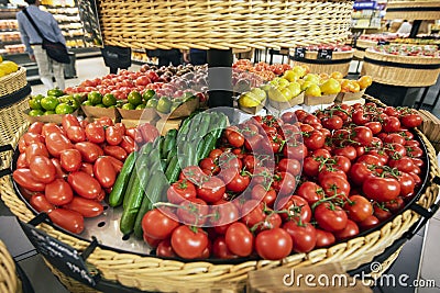 Vegetable basket with different types of tomatoes and cucumbers Stock Photo