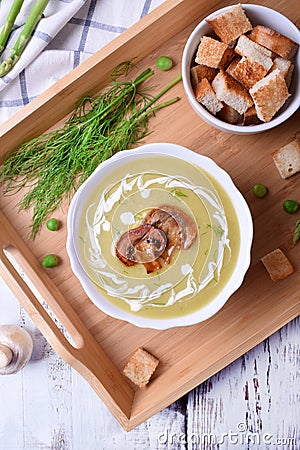 Vegetable cream soup with asparagus and peas garnished with cream and roasted champignons Stock Photo