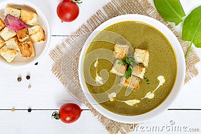 Vegetable cream soup with spinach and potatoes in a white bowl with garlic croutons on a dark wooden background. Stock Photo