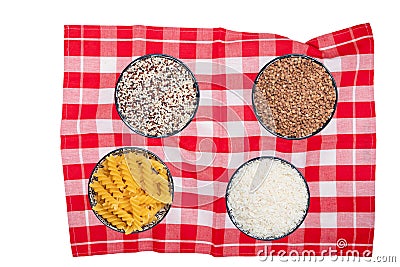 Vegetable food. Closeup of four bowls with buckwheat, noodles, rice and quinoa on a red checkered tablecloth isolated. Healthy Stock Photo