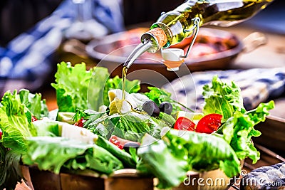 Vegetable lettuce salad. Olive oil pouring into bowl of salad. Italian Mediterranean or Greek cuisine. Vegetarian vegan food Stock Photo