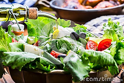 Vegetable lettuce salad. Olive oil pouring into bowl of salad. Italian Mediterranean or Greek cuisine. Vegetarian vegan food Stock Photo