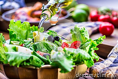 Vegetable lettuce salad. Olive oil pouring into bowl of salad. Italian Mediterranean or Greek cuisine. Vegetarian vegan food Stock Photo