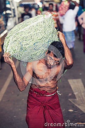 Vegetable market. Worker with heavy sack. Editorial Stock Photo