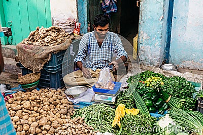 Vegetable merchant sell potato that weigh by digital scales in the morning market in Kolkata, India Editorial Stock Photo