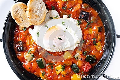 Vegetable pisto manchego with tomatoes, zucchini, peppers, onions,eggplant and egg, served in frying pan isolated on white Stock Photo
