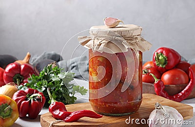 Vegetable salad with eggplant, carrot, peppers, onion and tomatoes in glass jar on wooden board, horizontal format. Closeup Stock Photo