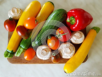 Vegetable still life. Vegetables on a cutting board on the kitchen table. Zucchini, tomatoes, champignons, peppers. Red, yellow, o Stock Photo