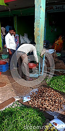 Vegetable vendor measuring goods weight at agriculture produce market Editorial Stock Photo