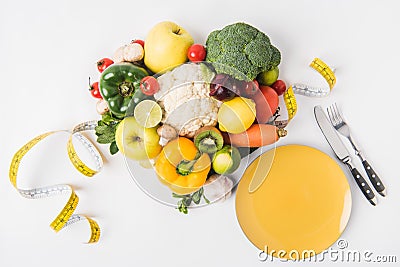 vegetables and fruits laying on white background with fork, spoon, measuring tape Stock Photo