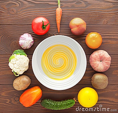 Vegetables and fruits lie around an empty plate on a wooden table. Stock Photo