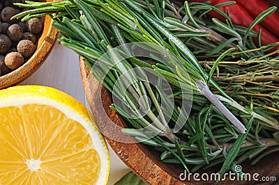 Vegetables and herbs as ingridients for chicken dish recipe: rosemary, lemon, allspice, thyme, chili pepper in round wooden plates Stock Photo