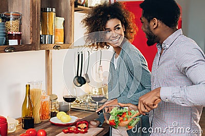 Vegetarian african-american couple cooking salad in kitchen Stock Photo