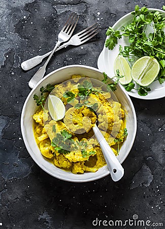 Vegetarian indian cauliflower curry sauce, cilantro, lime on dark background, top view. Delicious indian food concept Stock Photo