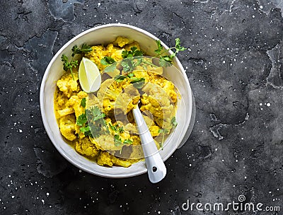 Vegetarian indian cauliflower stew with curry sauce, cilantro, lime on dark background, top view. Delicious indian food concept Stock Photo