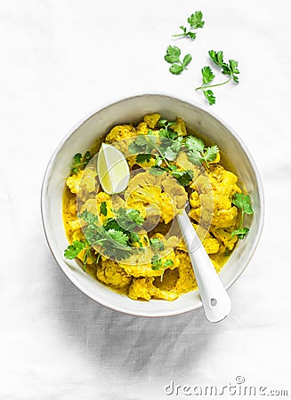 Vegetarian indian cauliflower stew with curry sauce, cilantro, lime on light background, top view. Delicious indian food concept Stock Photo