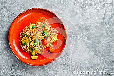 Vegetarian pasta with tomatoes, avacado and squash. Gray background, top view, space for text. Stock Photo