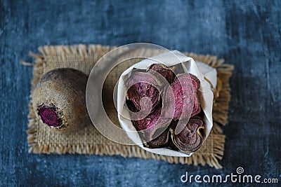 Vegetarian pile of healthy beet chips Purple Baked Beet Chips Vegan snacks, vegetable chips in canvas bag and ceramic bowl, rustic Stock Photo