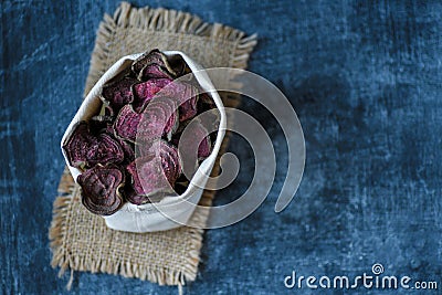 Vegetarian pile of healthy beet chips Purple Baked Beet Chips Vegan snacks, vegetable chips in canvas bag and ceramic bowl, rustic Stock Photo