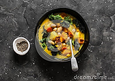 Vegetarian pumpkin, potatoes, beans and kale stew - delicious autumn lunch on a dark background, top view Stock Photo