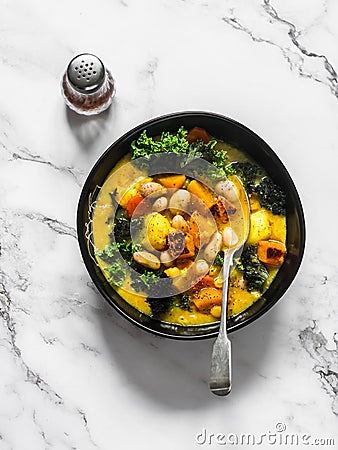 Vegetarian pumpkin, potatoes, beans and kale stew - delicious autumn lunch on a light background, top view Stock Photo