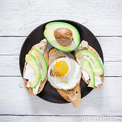 Vegetarian sandwiches with avocado and egg on a dark plate on wooden table. Flat lay. Top view. Tasty food concept Stock Photo