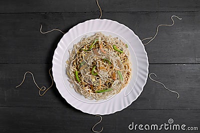 Vegetarian Schezwan Noodles or Vegetable Hakka Noodles or Chow Mein in white plate at wooden background. Schezwan Noodles is indo- Stock Photo