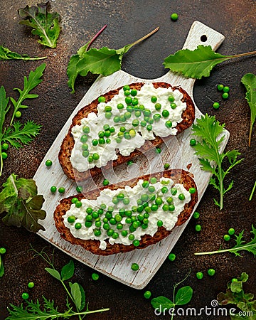 Vegetarian seeded sourdough bread open sandwich with cottage cheese and petit poit peas sprinkled with chilli flakes Stock Photo